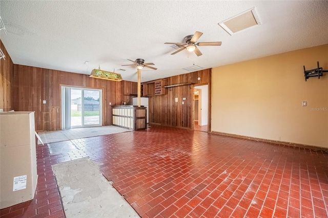 252 W Brookins Ave, Eagle Lake, FL 33839 - unfurnished living room featuring wood walls, a ceiling fan, brick patterned floors, and a textured ceiling