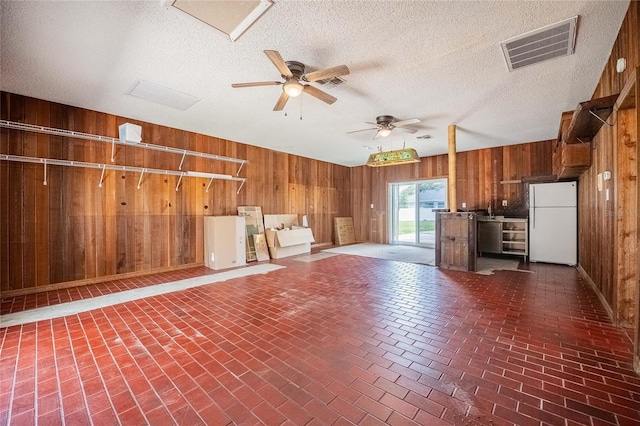 252 W Brookins Ave, Eagle Lake, FL 33839 - unfurnished living room featuring wooden walls, ceiling fan, brick patterned floors, and a textured ceiling