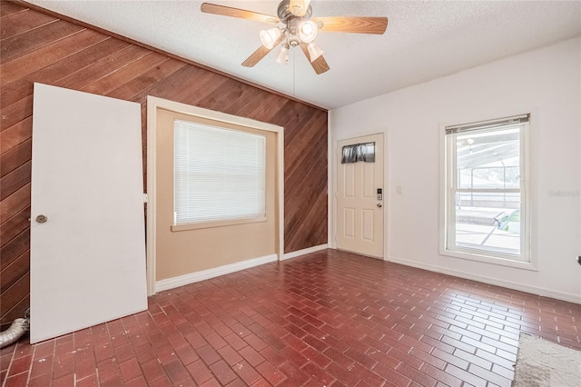 252 W Brookins Ave, Eagle Lake, FL 33839 - empty room featuring wooden walls, brick patterned flooring, ceiling fan, and a textured ceiling