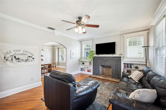 1515 King Ave, Lakeland, FL 33803 - living room featuring arched walkways, a ceiling fan, wood finished floors, ornamental molding, and a stone fireplace
