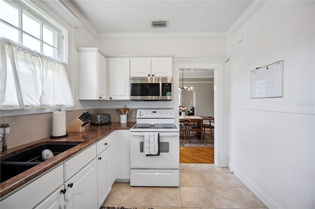 1515 King Ave, Lakeland, FL 33803 - kitchen featuring white electric range oven, stainless steel microwave, decorative backsplash, ornamental molding, and white cabinets