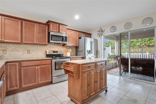 11607 Hammocks Glade Dr, Riverview, FL 33569 - kitchen with appliances with stainless steel finishes, light tile patterned floors, tasteful backsplash, brown cabinetry, and a center island