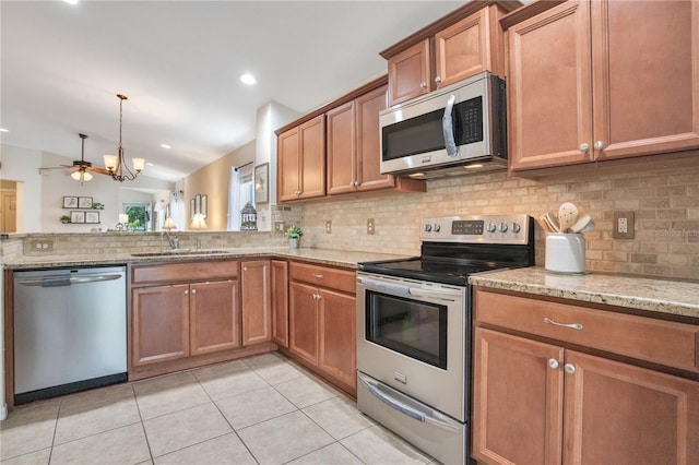 11607 Hammocks Glade Dr, Riverview, FL 33569 - kitchen featuring appliances with stainless steel finishes, decorative backsplash, brown cabinetry, light stone counters, and light tile patterned flooring