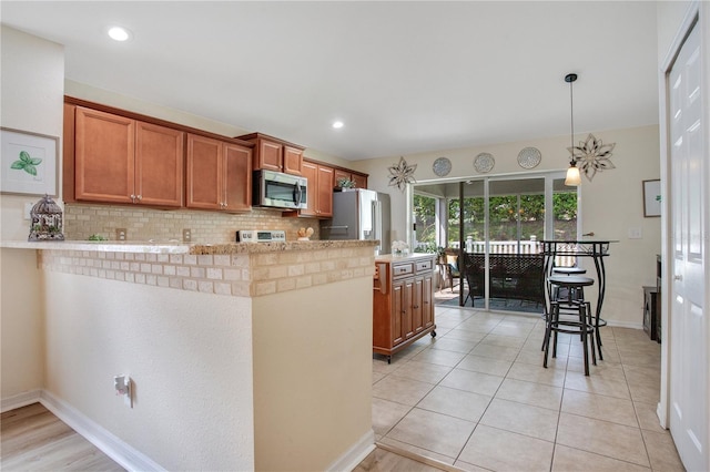 11607 Hammocks Glade Dr, Riverview, FL 33569 - kitchen with stainless steel appliances, a peninsula, backsplash, brown cabinets, and light countertops