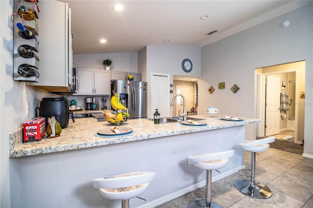 8031 Brookeshire Dr, Lakeland, FL 33809 - kitchen featuring stainless steel fridge with ice dispenser, vaulted ceiling, a peninsula, a breakfast bar, and light tile patterned flooring