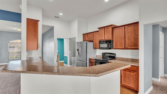 1156 Normandy Heights Cir, Winter Haven, FL 33880 - kitchen with black appliances, brown cabinetry, a peninsula, light carpet, and recessed lighting