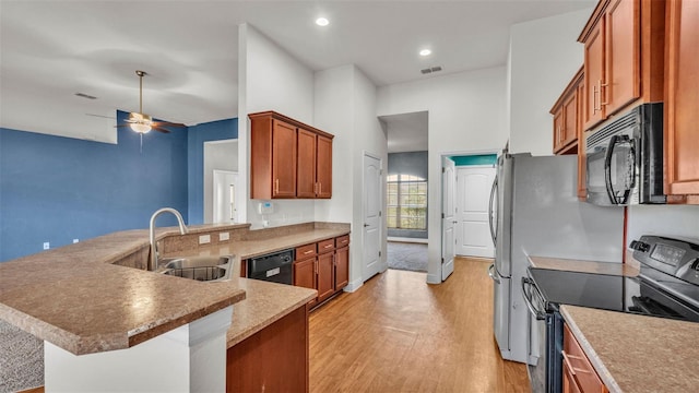 1156 Normandy Heights Cir, Winter Haven, FL 33880 - kitchen with black appliances, light wood finished floors, ceiling fan, brown cabinets, and a peninsula