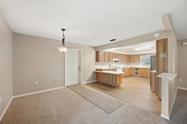335 W Cummings St, Lake Alfred, FL 33850 - kitchen featuring white range with electric cooktop, light colored carpet, a peninsula, light countertops, and brown cabinetry