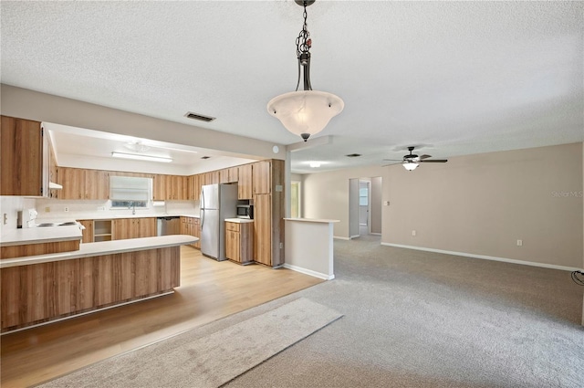 335 W Cummings St, Lake Alfred, FL 33850 - kitchen with stainless steel appliances, a peninsula, open floor plan, brown cabinets, and a textured ceiling