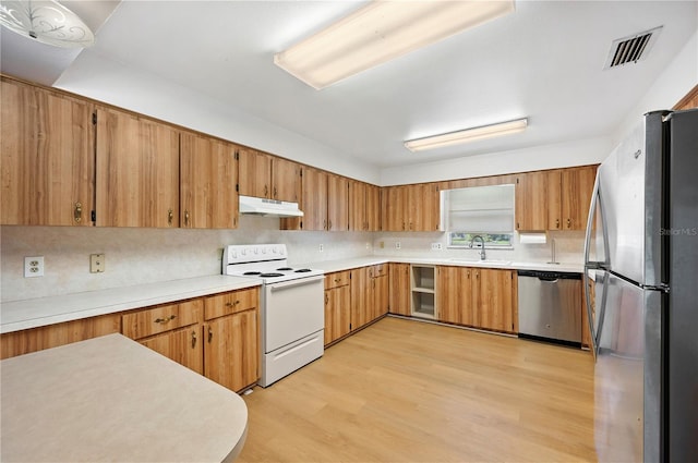335 W Cummings St, Lake Alfred, FL 33850 - kitchen featuring stainless steel appliances, under cabinet range hood, light wood finished floors, brown cabinetry, and light countertops