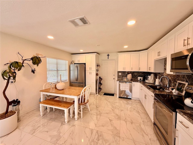 1302 W 8th St, Lakeland, FL 33805 - kitchen with appliances with stainless steel finishes, light marble finish flooring, recessed lighting, white cabinetry, and decorative backsplash