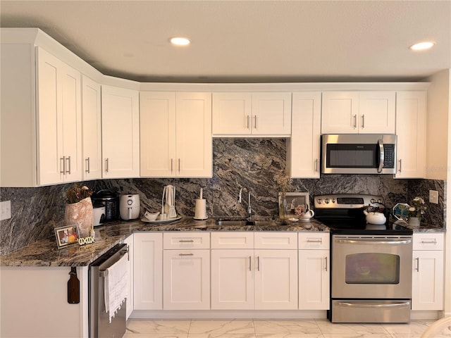 1302 W 8th St, Lakeland, FL 33805 - kitchen with stainless steel appliances, light marble finish flooring, white cabinets, dark stone counters, and backsplash