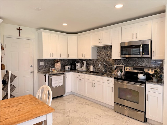 1302 W 8th St, Lakeland, FL 33805 - kitchen with appliances with stainless steel finishes, light marble finish flooring, white cabinetry, dark stone countertops, and recessed lighting
