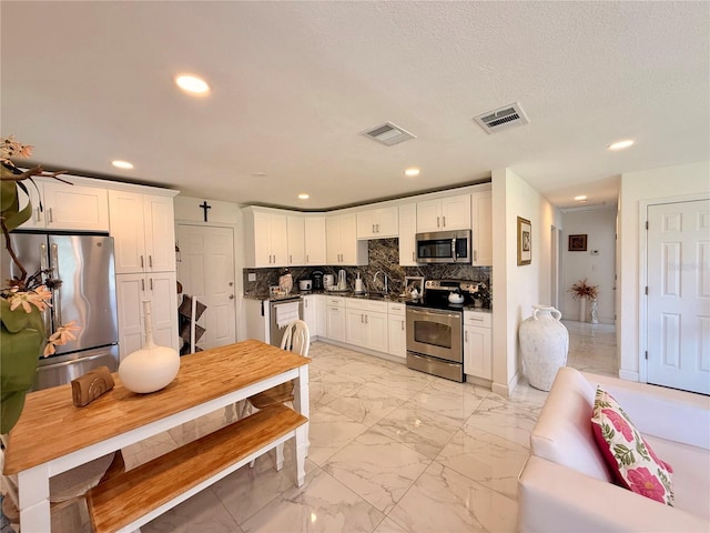 1302 W 8th St, Lakeland, FL 33805 - kitchen featuring appliances with stainless steel finishes, recessed lighting, white cabinetry, backsplash, and light marble finish flooring