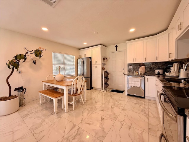 1302 W 8th St, Lakeland, FL 33805 - kitchen featuring appliances with stainless steel finishes, dark countertops, recessed lighting, white cabinets, and decorative backsplash