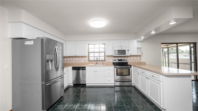 6504 Hereford Dr, Lakeland, FL 33810 - kitchen with appliances with stainless steel finishes, a peninsula, light countertops, white cabinetry, and decorative backsplash