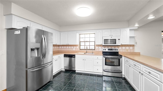6504 Hereford Dr, Lakeland, FL 33810 - kitchen featuring appliances with stainless steel finishes, white cabinets, light countertops, decorative backsplash, and a textured ceiling