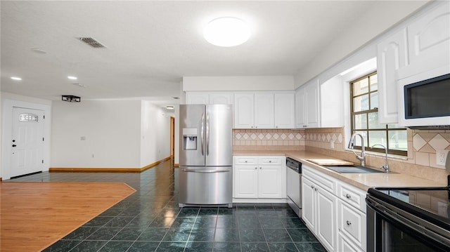 6504 Hereford Dr, Lakeland, FL 33810 - kitchen with appliances with stainless steel finishes, white cabinets, decorative backsplash, dark tile patterned flooring, and recessed lighting