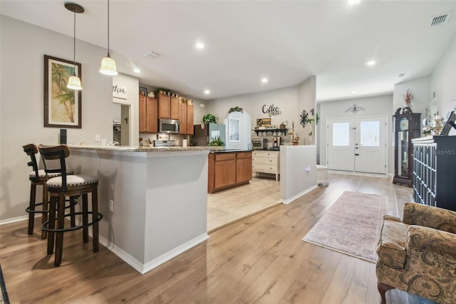 1933 Griffin Trl, Bartow, FL 33830 - kitchen with appliances with stainless steel finishes, brown cabinets, light wood-style flooring, a peninsula, and a breakfast bar