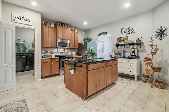 1933 Griffin Trl, Bartow, FL 33830 - kitchen with appliances with stainless steel finishes, washing machine and dryer, a center island, brown cabinetry, and arched walkways