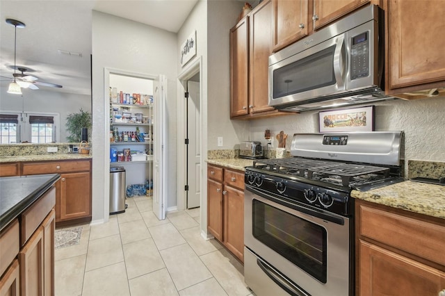 1933 Griffin Trl, Bartow, FL 33830 - kitchen featuring stainless steel appliances, a ceiling fan, brown cabinetry, and light tile patterned flooring