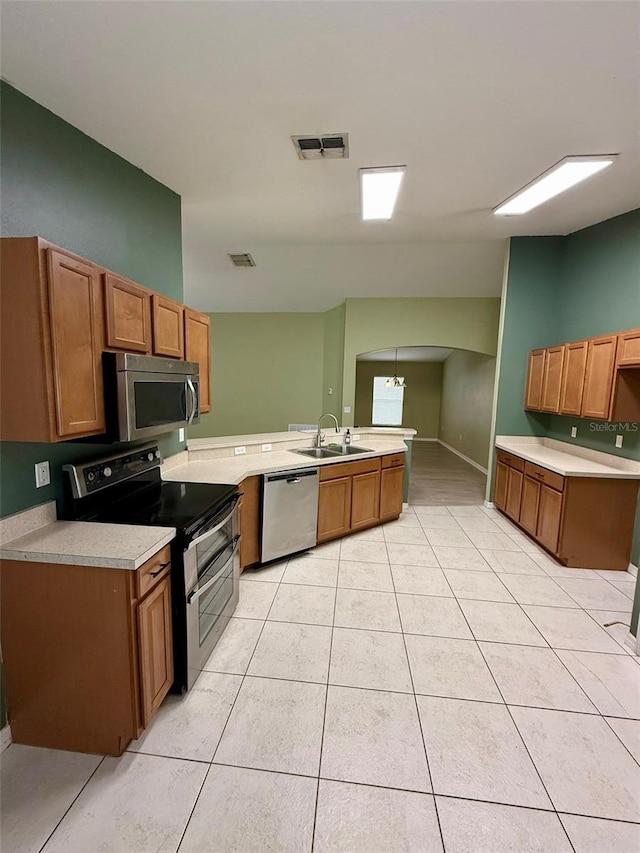 7198 Cedarcrest Blvd, Lakeland, FL 33810 - kitchen featuring appliances with stainless steel finishes, a peninsula, light tile patterned flooring, arched walkways, and light countertops