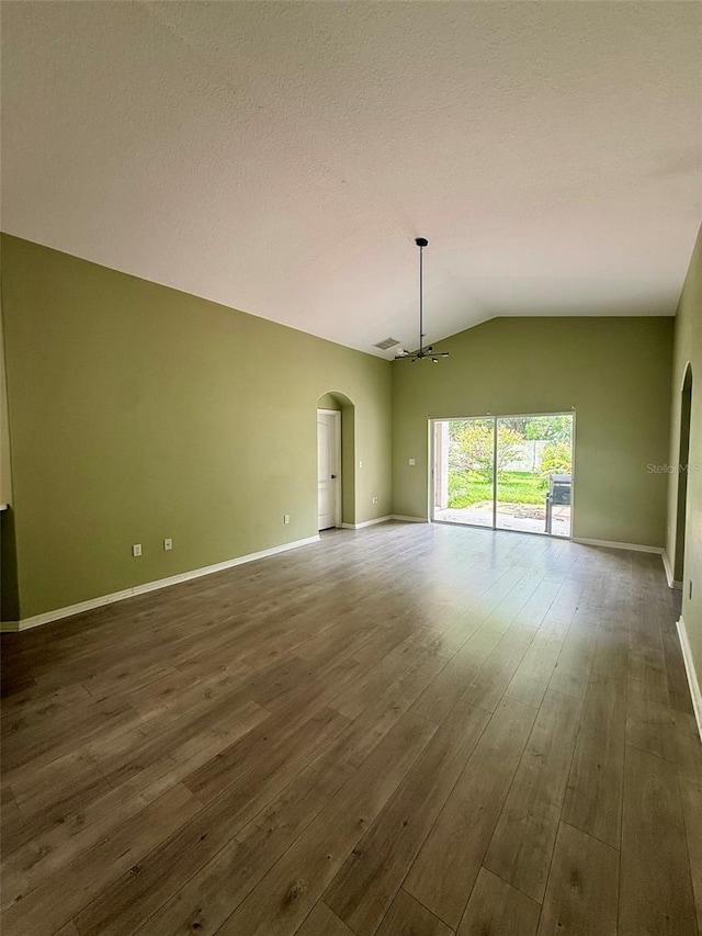 7198 Cedarcrest Blvd, Lakeland, FL 33810 - empty room featuring arched walkways, lofted ceiling, dark wood finished floors, and a chandelier