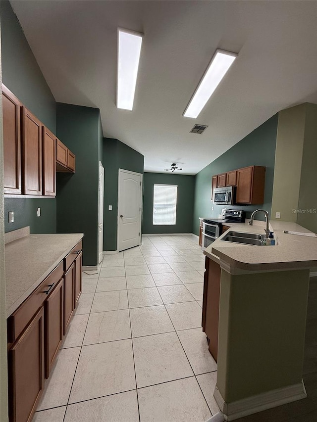 7198 Cedarcrest Blvd, Lakeland, FL 33810 - kitchen featuring appliances with stainless steel finishes, a peninsula, light countertops, light tile patterned floors, and vaulted ceiling
