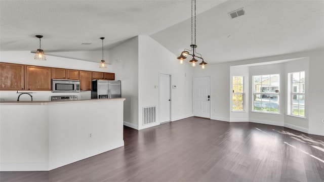 3917 NW Warbler Dr, Winter Haven, FL 33880 - kitchen featuring appliances with stainless steel finishes, brown cabinetry, dark wood-type flooring, hanging light fixtures, and a textured ceiling