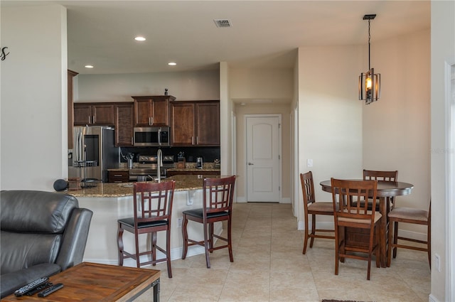 702 Country Walk Cv, Eagle Lake, FL 33839 - kitchen featuring stainless steel appliances, dark brown cabinetry, a breakfast bar area, light stone counters, and recessed lighting