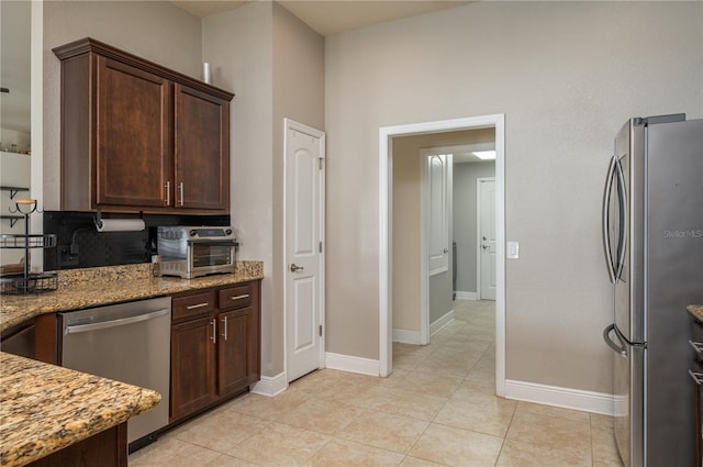 702 Country Walk Cv, Eagle Lake, FL 33839 - kitchen with stainless steel appliances, light stone counters, dark brown cabinets, and light tile patterned flooring