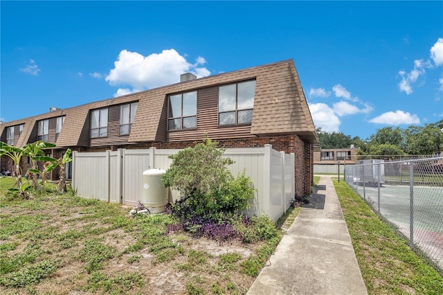 1836 N Crystal Lake Dr Unit 11, Lakeland, FL 33801 - view of side of property with mansard roof, brick siding, a shingled roof, and a chimney