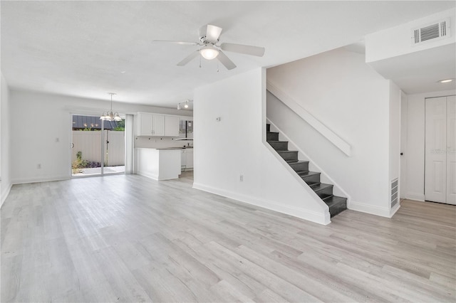 1836 N Crystal Lake Dr Unit 11, Lakeland, FL 33801 - unfurnished living room with a chandelier, ceiling fan, stairway, and light wood-style flooring