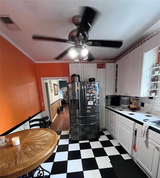 1319 Florida Ave, Saint Cloud, FL 34769 - kitchen with dark flooring, refrigerator with ice dispenser, a ceiling fan, glass insert cabinets, and light countertops