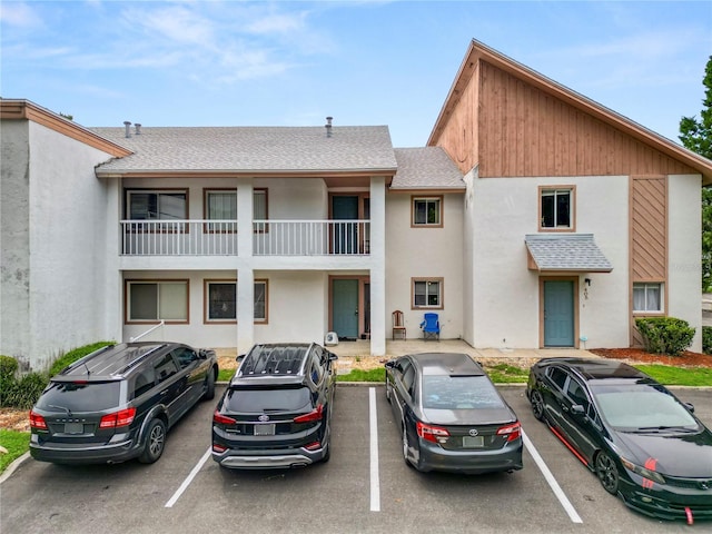 404 Country Ln NE Unit 404, Winter Haven, FL 33881 - view of front of home with stucco siding, a shingled roof, and uncovered parking