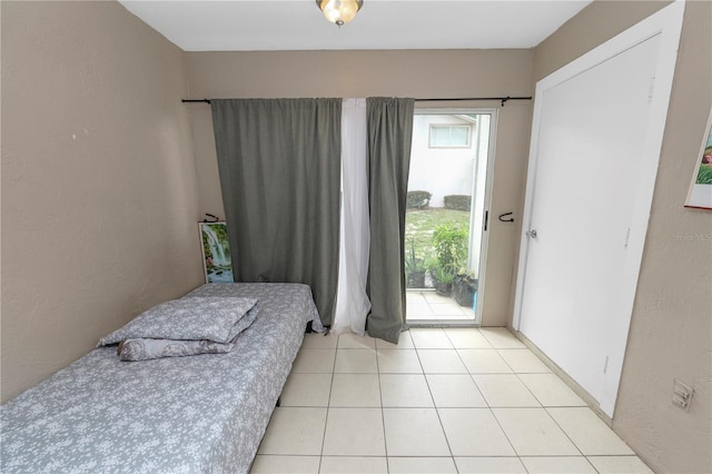 404 Country Ln NE Unit 404, Winter Haven, FL 33881 - bedroom featuring access to exterior, light tile patterned flooring, and a textured wall