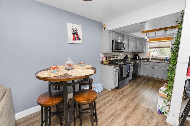 404 Country Ln NE Unit 404, Winter Haven, FL 33881 - kitchen with gray cabinetry, stainless steel appliances, light wood-type flooring, and backsplash