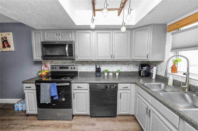 404 Country Ln NE Unit 404, Winter Haven, FL 33881 - kitchen featuring stainless steel appliances, light wood finished floors, tasteful backsplash, a raised ceiling, and a textured ceiling