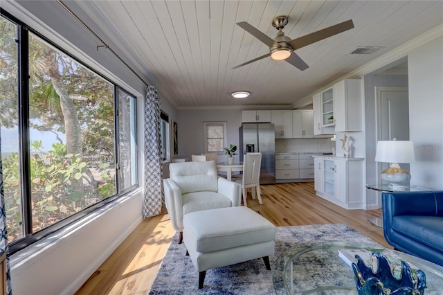 living room with crown molding, ceiling fan, a wealth of natural light, and light hardwood / wood-style flooring