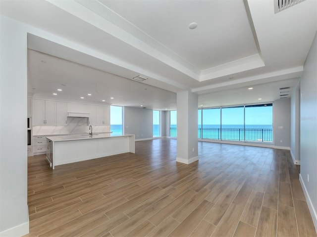 unfurnished living room featuring sink, a water view, and light wood-type flooring