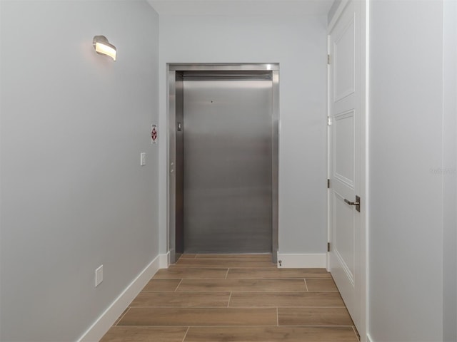 hall with elevator and light wood-type flooring