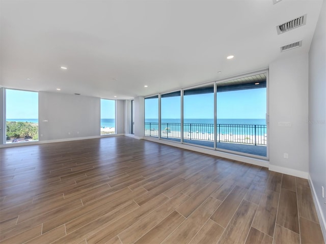 spare room featuring a water view, light hardwood / wood-style flooring, and floor to ceiling windows