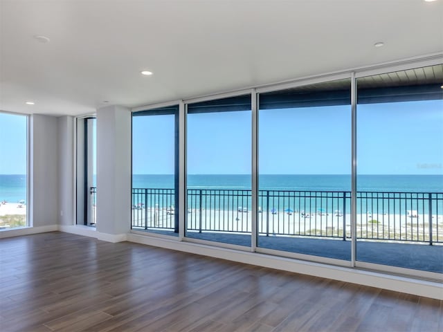 spare room featuring a view of the beach, wood-type flooring, and a water view