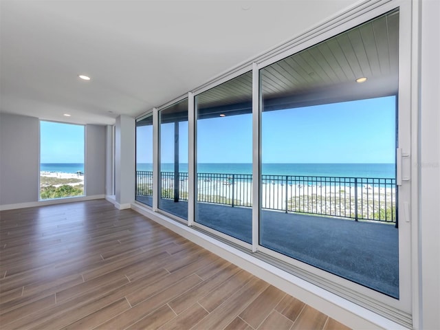 unfurnished sunroom featuring a view of the beach and a water view