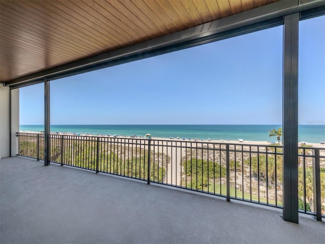 unfurnished sunroom with a water view, wooden ceiling, and a beach view