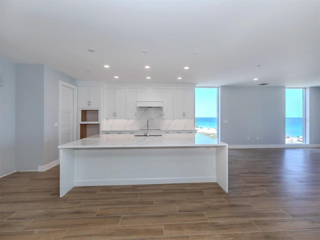 kitchen with white cabinets, dark hardwood / wood-style flooring, a large island, and sink