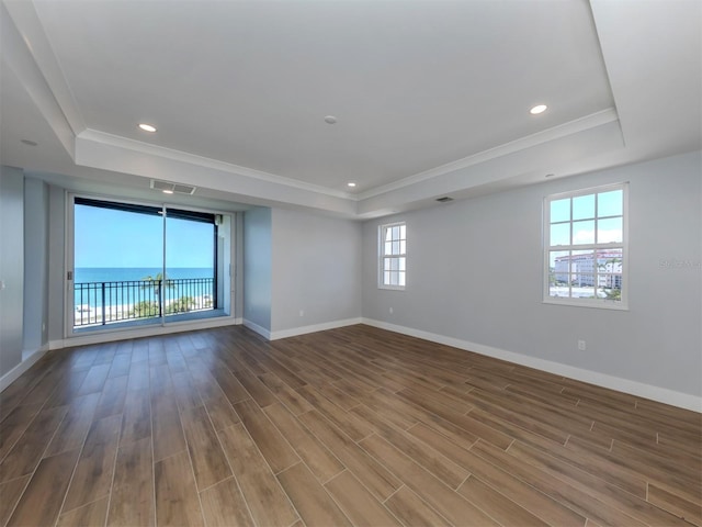 empty room with hardwood / wood-style floors, a water view, ornamental molding, and a tray ceiling