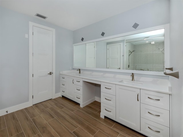 bathroom featuring hardwood / wood-style flooring, vanity, and a tile shower