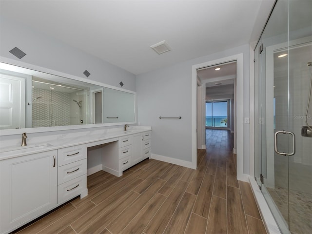 bathroom with hardwood / wood-style floors, vanity, and a shower with door