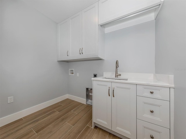 clothes washing area with hookup for an electric dryer, washer hookup, cabinets, sink, and light hardwood / wood-style flooring